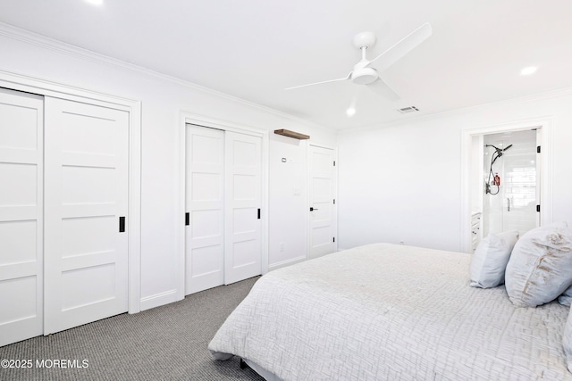 carpeted bedroom with crown molding, ceiling fan, connected bathroom, and two closets