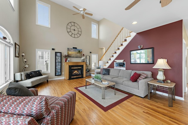 living room with wood-type flooring, a towering ceiling, and ceiling fan