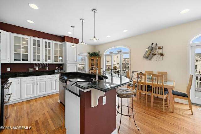 kitchen with white cabinetry, a breakfast bar, light wood-type flooring, and decorative light fixtures