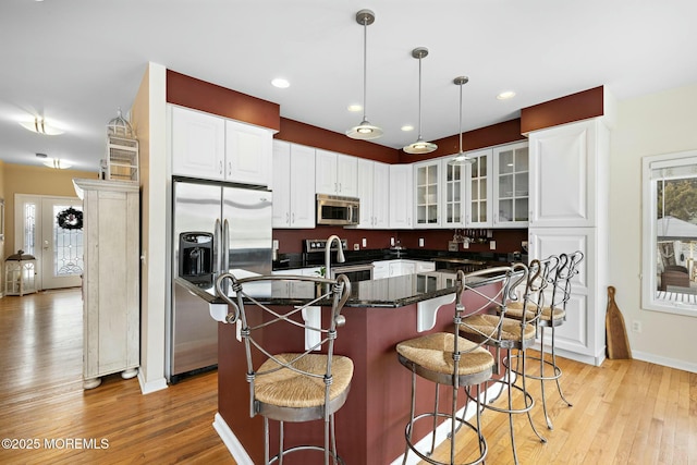 kitchen featuring white cabinetry, stainless steel appliances, a kitchen island with sink, and a breakfast bar area