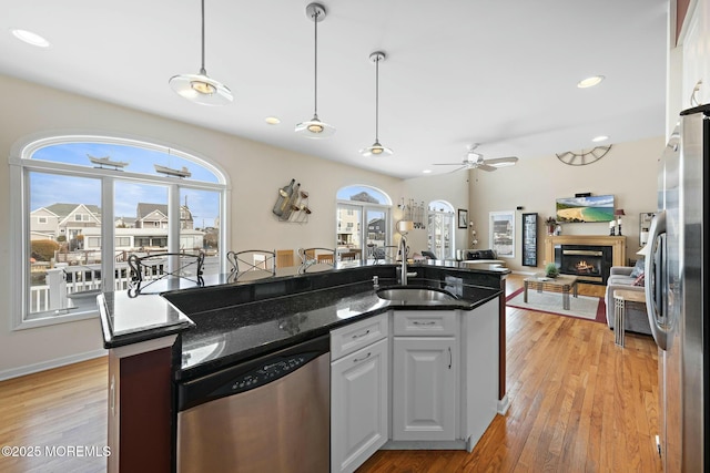 kitchen featuring sink, light hardwood / wood-style flooring, white cabinetry, stainless steel appliances, and decorative light fixtures