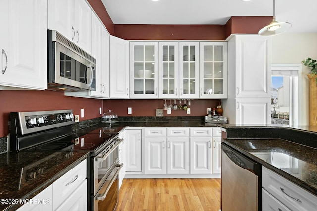 kitchen featuring stainless steel appliances, decorative light fixtures, and white cabinets