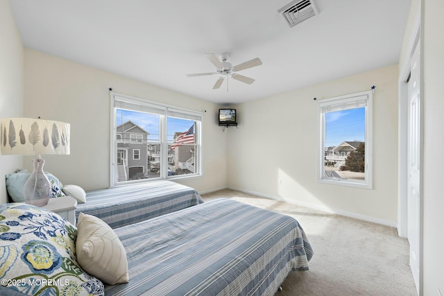 bedroom featuring multiple windows, light carpet, ceiling fan, and a closet