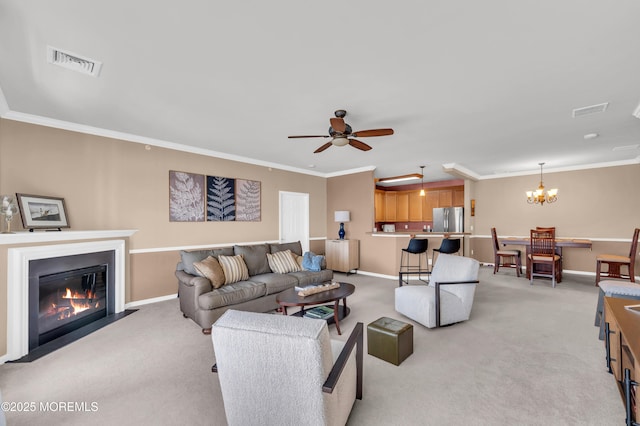 living room featuring ornamental molding, ceiling fan with notable chandelier, and light colored carpet