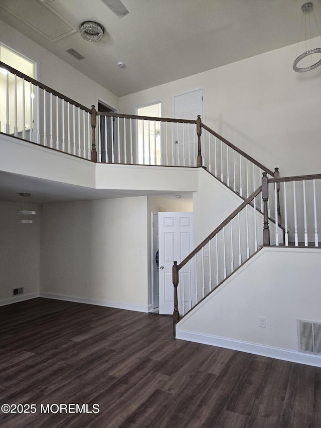 staircase with wood-type flooring and a high ceiling