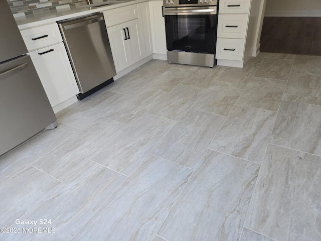 kitchen featuring stainless steel appliances, tasteful backsplash, and white cabinets