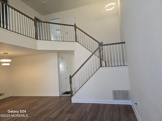 stairway with hardwood / wood-style flooring and a high ceiling