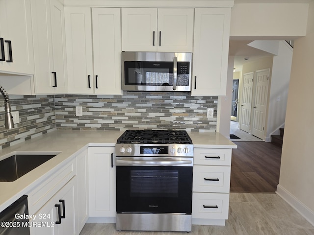 kitchen with sink, light hardwood / wood-style flooring, white cabinetry, stainless steel appliances, and decorative backsplash