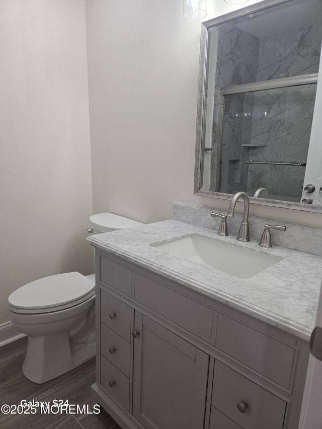 bathroom with walk in shower, vanity, toilet, and wood-type flooring