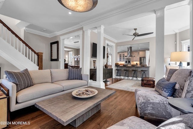 living room with decorative columns, ornamental molding, dark hardwood / wood-style floors, and ceiling fan