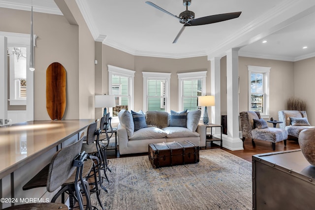 living room featuring hardwood / wood-style floors, ornamental molding, decorative columns, and ceiling fan