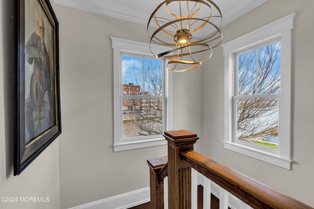 hall with an inviting chandelier and crown molding