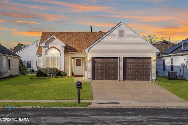 view of front of home with a garage, central AC unit, and a lawn