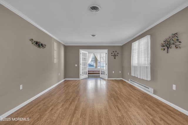 spare room featuring ornamental molding, a baseboard heating unit, and light hardwood / wood-style flooring