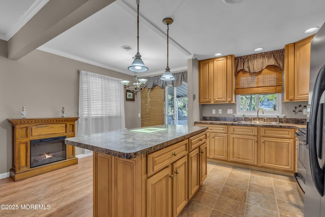 kitchen featuring sink, hanging light fixtures, fridge, ornamental molding, and a kitchen island