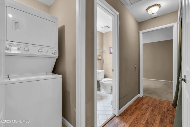 laundry room featuring hardwood / wood-style flooring and stacked washer / drying machine