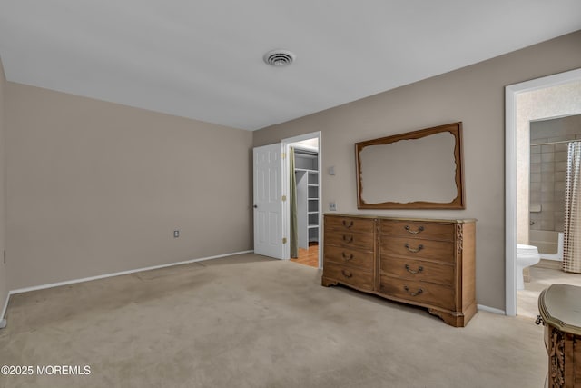 bedroom featuring a walk in closet, connected bathroom, light colored carpet, and a closet