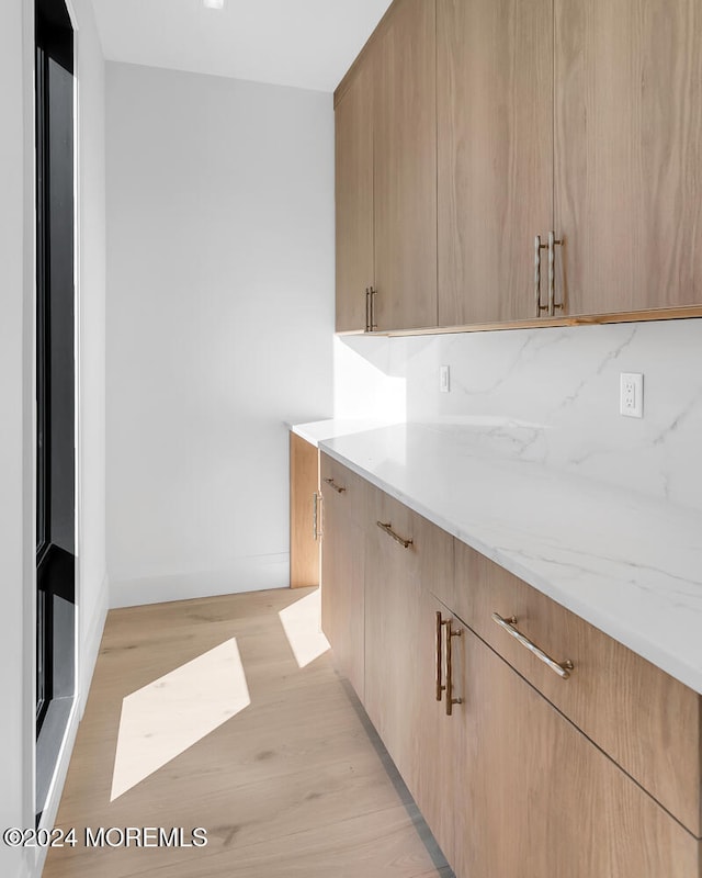 kitchen with light stone counters, light brown cabinetry, and light hardwood / wood-style floors