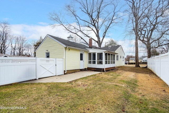 rear view of property featuring a yard, a patio, and a sunroom