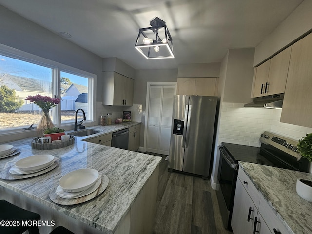 kitchen with dark wood-type flooring, sink, light stone counters, stainless steel appliances, and backsplash