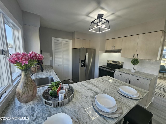 kitchen featuring stainless steel appliances, light stone countertops, sink, and decorative backsplash