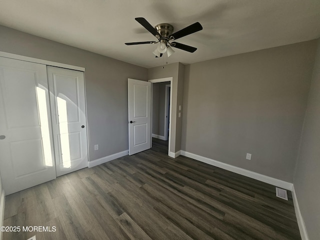 unfurnished bedroom featuring dark wood-type flooring, a closet, and ceiling fan