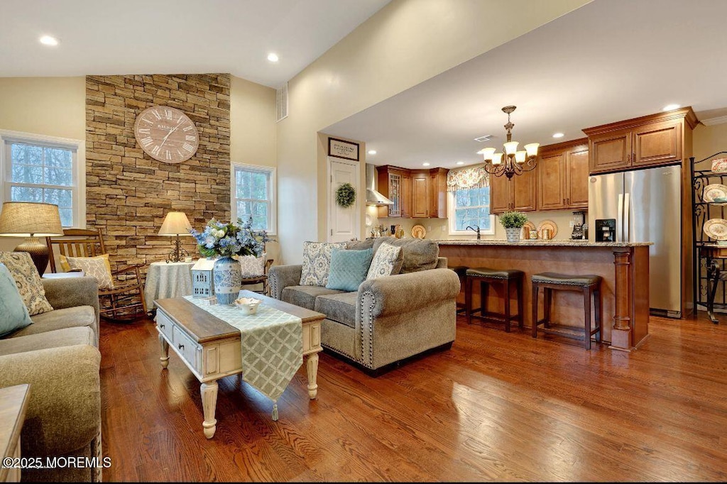 living room featuring high vaulted ceiling, sink, an inviting chandelier, and dark hardwood / wood-style flooring