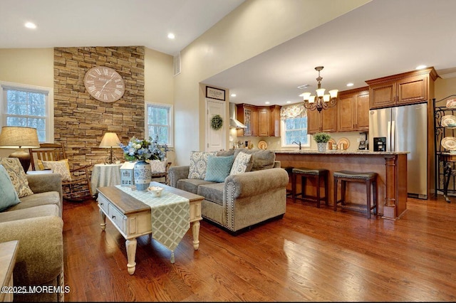 living room featuring high vaulted ceiling, sink, an inviting chandelier, and dark hardwood / wood-style flooring