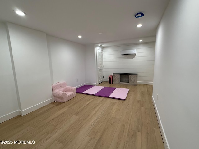 exercise area featuring a wall unit AC and light hardwood / wood-style flooring