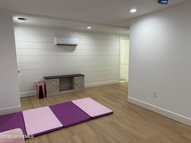 exercise room featuring a wall mounted AC and light hardwood / wood-style floors