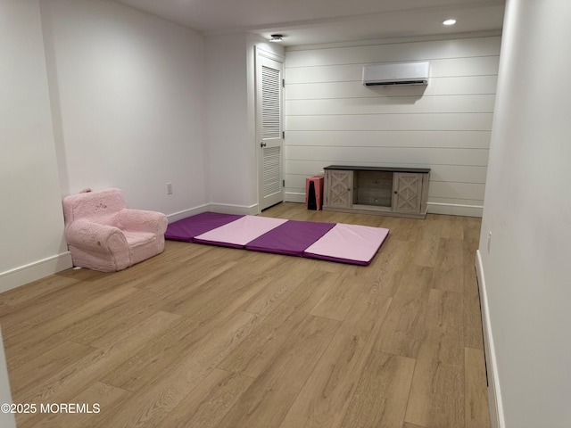 exercise room featuring a wall mounted air conditioner and light hardwood / wood-style floors