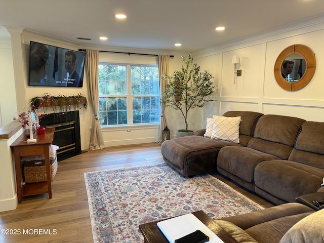 living room with ornamental molding, light hardwood / wood-style floors, and a tile fireplace