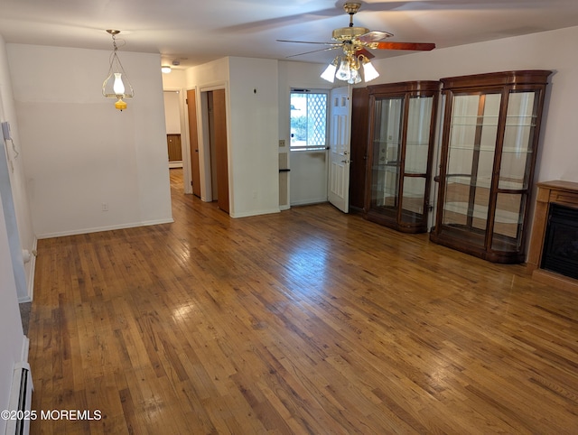 unfurnished living room featuring a baseboard heating unit, hardwood / wood-style floors, and ceiling fan