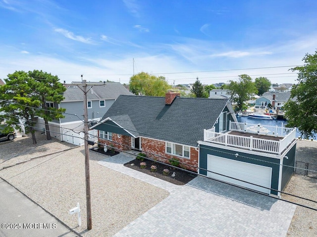 view of front of house featuring a garage, a balcony, and a water view