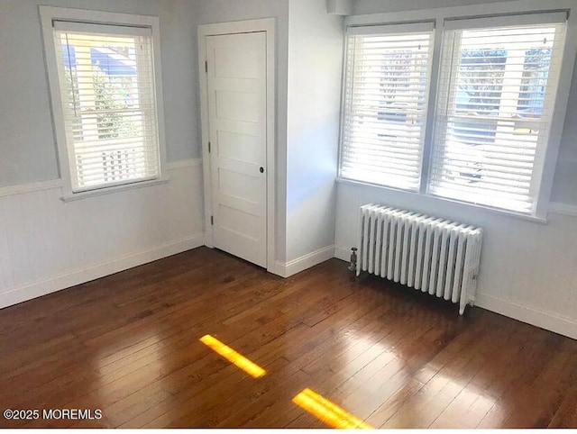 interior space featuring plenty of natural light, radiator heating unit, and dark hardwood / wood-style flooring