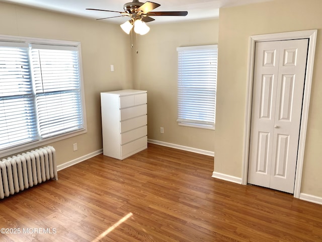 unfurnished bedroom with radiator, hardwood / wood-style flooring, and ceiling fan