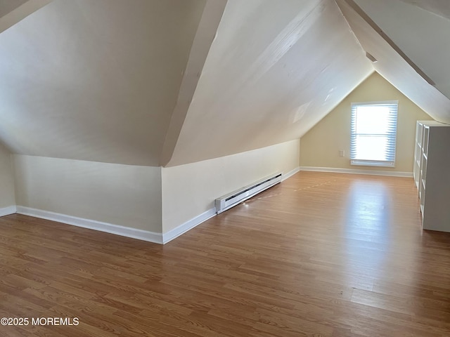 additional living space featuring hardwood / wood-style flooring, lofted ceiling, and a baseboard heating unit