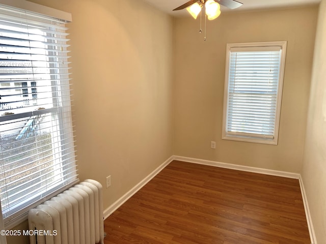 spare room featuring radiator, dark hardwood / wood-style floors, and ceiling fan