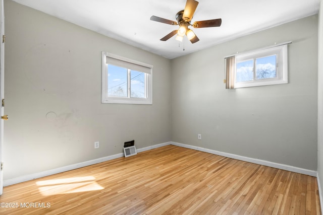 spare room with ceiling fan, a wealth of natural light, and light hardwood / wood-style floors