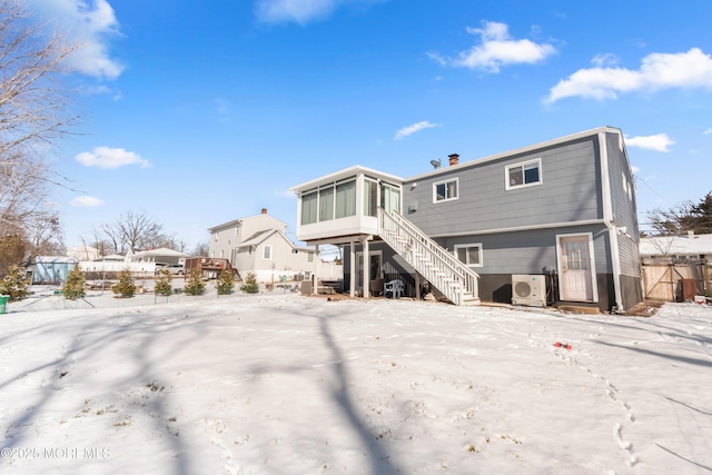 snow covered property with ac unit and a sunroom