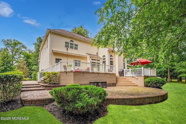 rear view of house with a wooden deck, a yard, and a patio