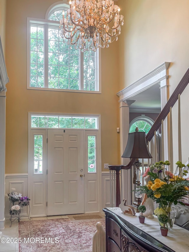 entryway featuring light tile patterned flooring, a towering ceiling, and a chandelier