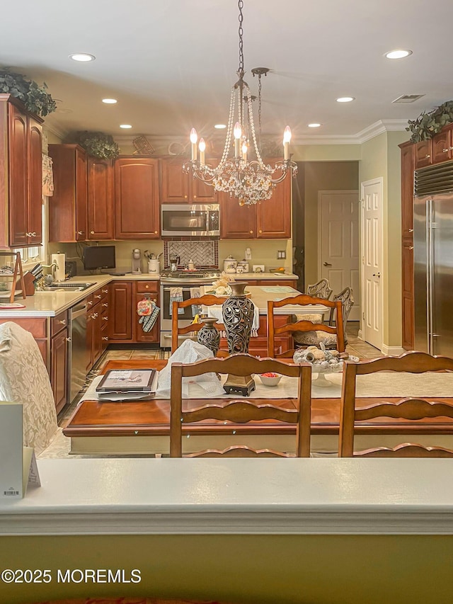 kitchen with sink, crown molding, appliances with stainless steel finishes, tasteful backsplash, and decorative light fixtures