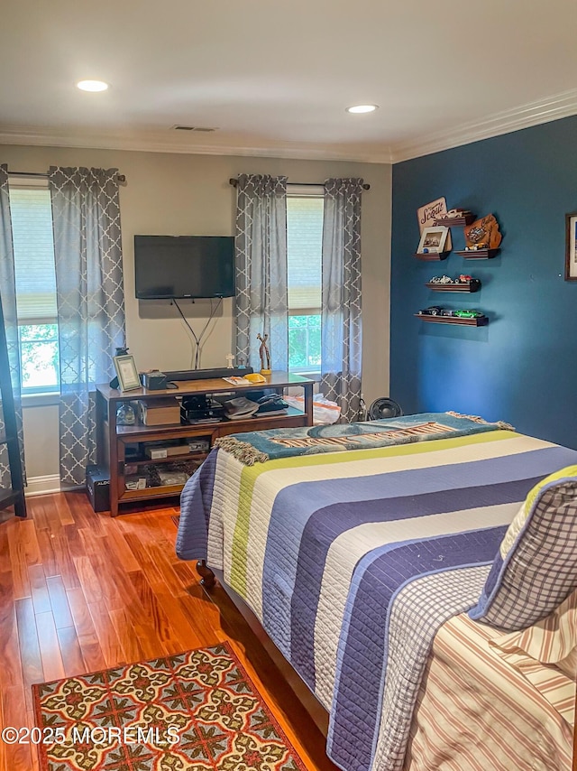 bedroom with crown molding, wood-type flooring, and multiple windows