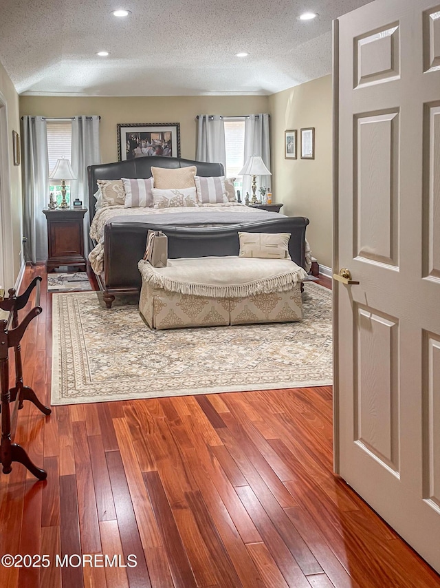 bedroom featuring multiple windows, hardwood / wood-style flooring, and a textured ceiling