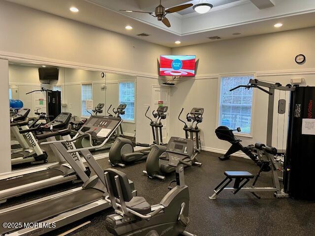 exercise room featuring crown molding, ceiling fan, and a tray ceiling