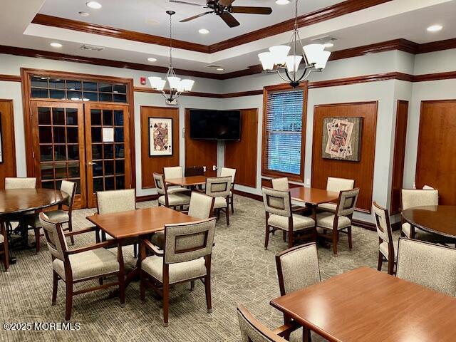 carpeted dining space featuring french doors, ornamental molding, and a raised ceiling