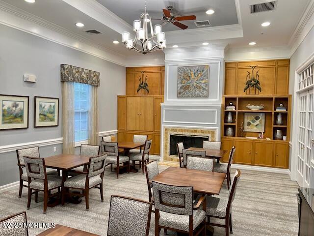 dining room featuring a tiled fireplace, ornamental molding, and a tray ceiling