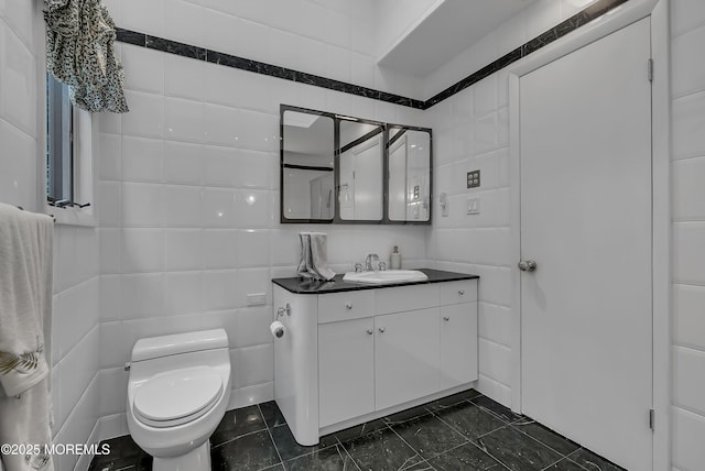 bathroom featuring vanity, toilet, and tile walls