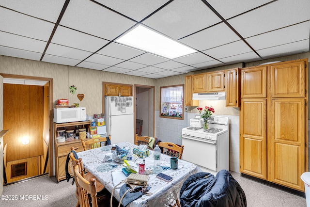 dining space with a paneled ceiling and light colored carpet